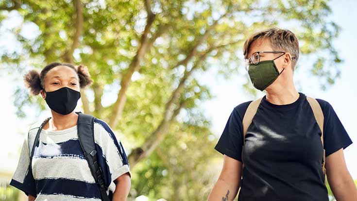 Two students wearing masks while walking outside
